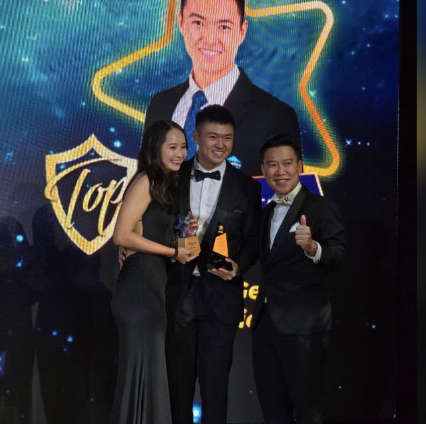 Damien Tan on stage receiving a Top Producer award